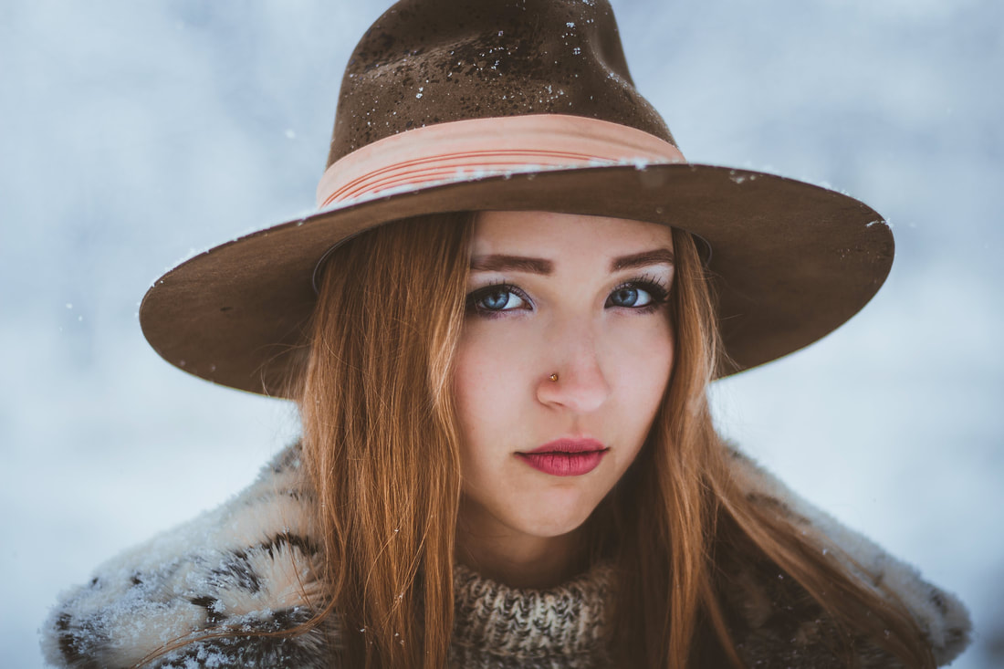 A woman wearing a hat ith makeup on during winter.