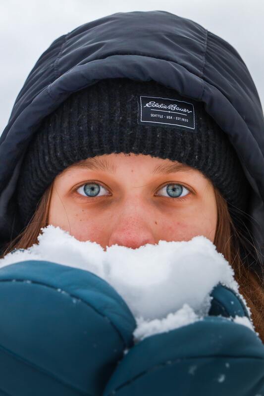 A woman is holding snow in front of her face.