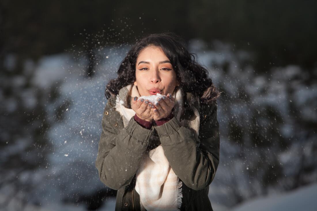 Woman with dark hair with snow in her hands