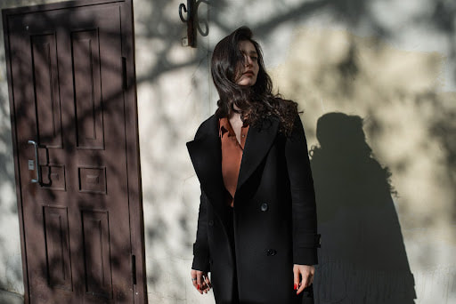 Model with dark hair standing by a door