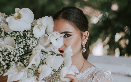 Bride hiding half her face behind a white bouquet